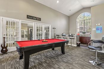 A pool table is in the middle of a room with a sign that says "Feel the Vibes".
